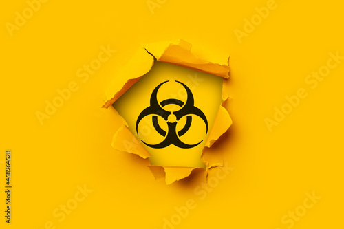 Bright yellow torn paper cardboard inside in a hole sign of radiation on a yellow background. photo