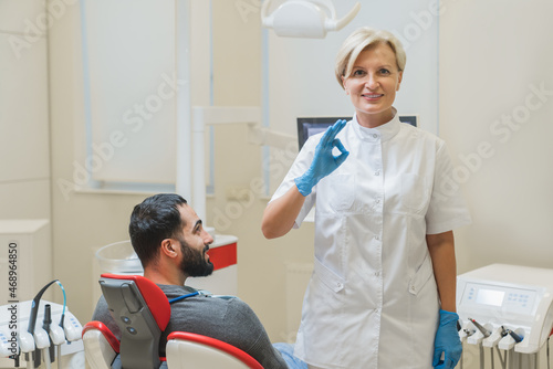 Doctor s checkup. Female caucasian dentist orthodontist showing okay gesture while curing patient in dental clinic. Stomatology concept