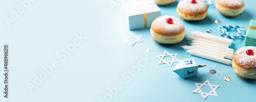 Jewish holiday Hanukkah concept - Hanukkah sweet doughnut with powdered sugar and fruit jam, gift boxes on blue paper background.