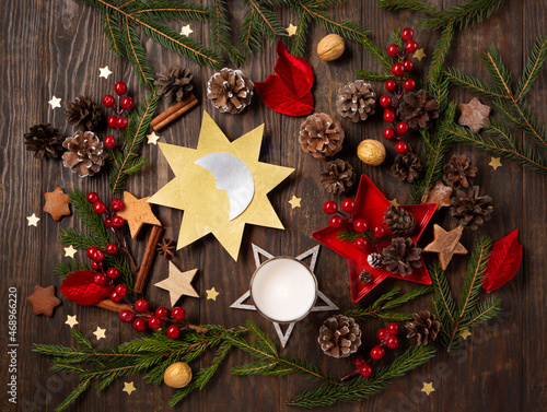 Winter solstice day, December 21. Sun and moon symbol, Christmas trees, pine cones, paddub branches with red berries, candle on dark wooden background, top view. photo