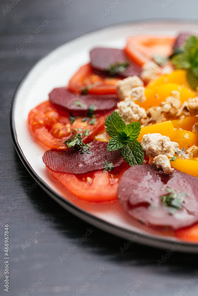 Plate with a home made vegan beet, tomato, and peach salad with vegan feta. Plate with a home made vegan beet, tomato, and peach salad with vegan feta.