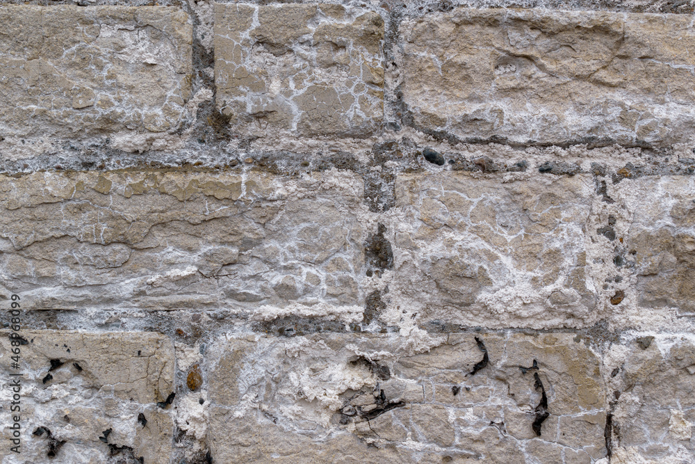 Vintage concrete block wall. White bloom, cracks, exfoliation.