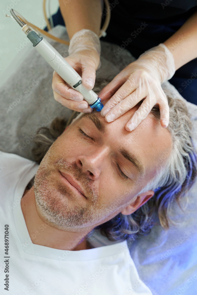 Middle aged man during deep facial cleansing in a cosmetology clinic Middle aged man during deep facial cleansing in a cosmetology clinic