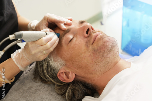 Middle aged man during deep facial cleansing in a cosmetology clinic