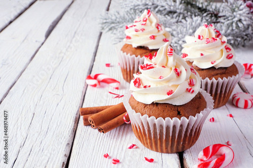 Christmas candy cane cupcakes with creamy frosting. Close up on a rustic white wood table background with copy space. photo