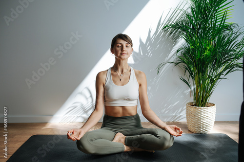 Relaxed 30 year old woman practicing yoga, meditating. Frontal view