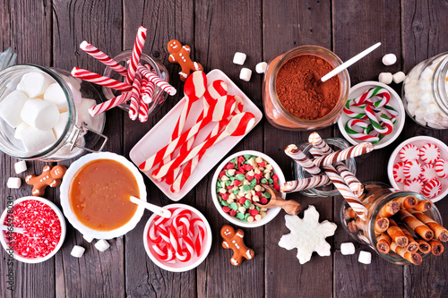 Christmas hot chocolate bar with a mixture of sweet toppings. Top view table scene on a dark wood background. photo