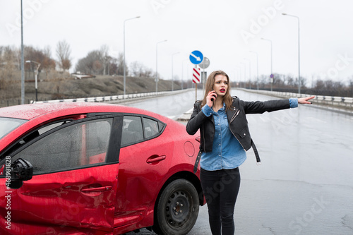 Woman calls to a service standing by a red car. Beautiful woman catches the car © Artem Zakharov