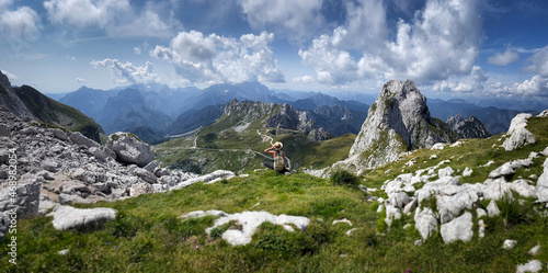 Young girl enjoying beauty of nature looking at mountains in europe. Adventure travel in Slovenia. Beautiful woman standing back on background with forest and Alps. Freedom lifestyle