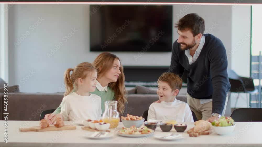Young happy family talking while having breakfast at dining table at apartment Young happy family talking while having breakfast at dining table at apartment