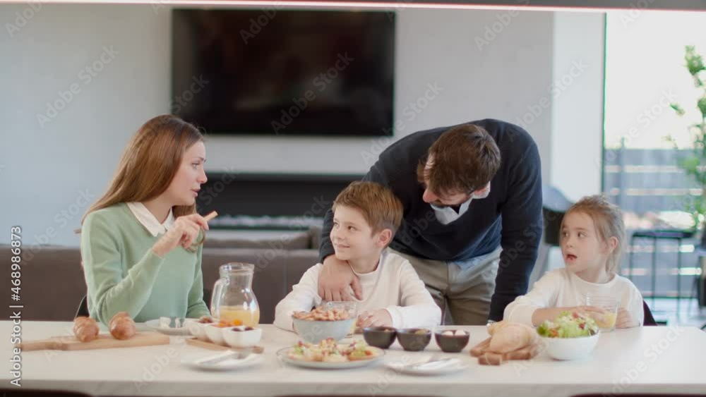 Young happy family talking while having breakfast at dining table at apartment Young happy family talking while having breakfast at dining table at apartment