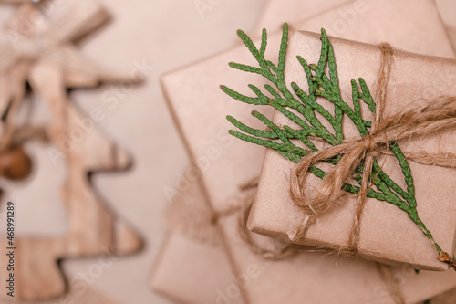Festive decoration of gifts in eco-style.Gift boxes are wrapped in craft paper,tied with cotton thread,decorated with thuja leaves and burlap,close-up.Christmas,New Year and eco-friendly concept.