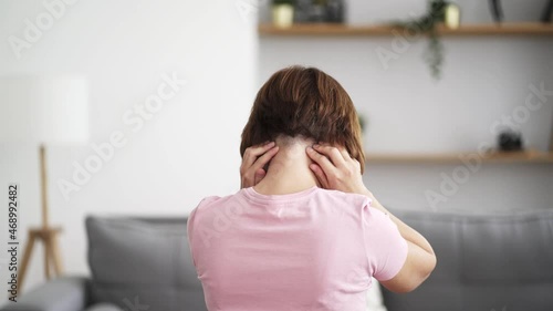A woman does self-massage of his neck and head at home, self-soothing massaging