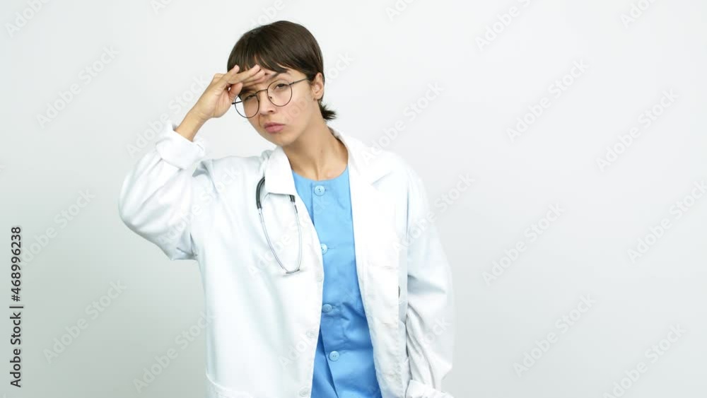 Young woman with nurse uniform looking far away with hand to look something over isolated background Young woman with nurse uniform looking far away with hand to look something over isolated background