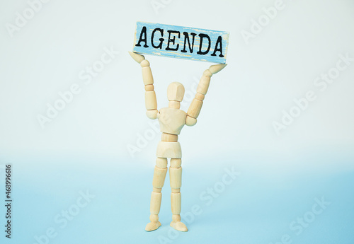 Wooden man shows with hand to block with text AGENDA photo