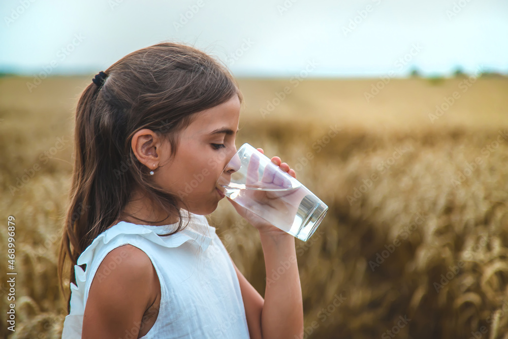 Obraz na plátně The child drinks water from a glass. Selective focus.