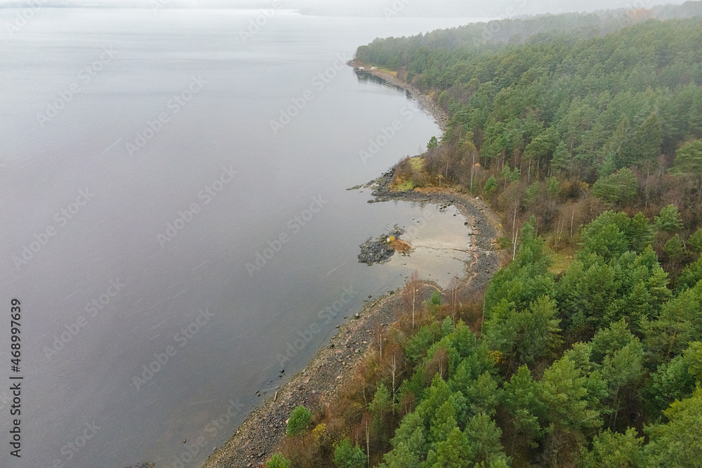 Obraz premium Karelia, Onega Lake, Petrozavodsk Bay. Aerial photography showing the forest and the coast, near the botanical garden. The water surface of the lake and the autumn forest. Vacation in Russia concept.