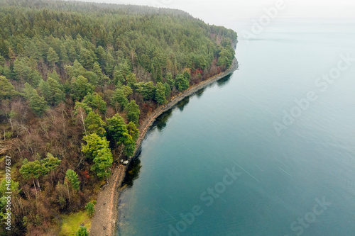Karelia, Onega Lake, Petrozavodsk Bay. Aerial photography showing the forest and the coast, near the botanical garden. The water surface of the lake and the autumn forest. Vacation in Russia concept.