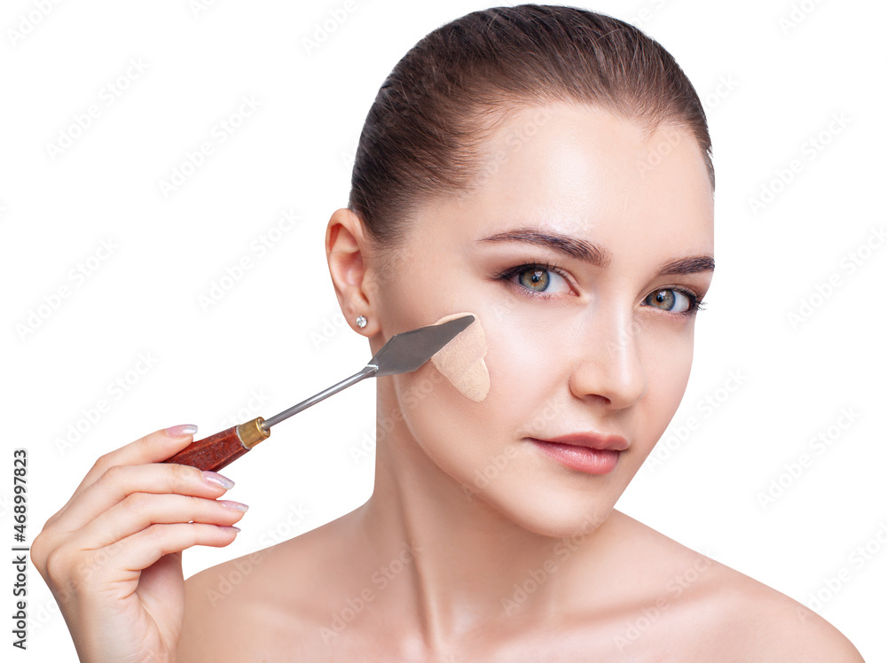 Young woman applying foundation with artistic spatula. Beauty Concept.