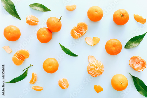 Fototapeta Naklejka Na Ścianę i Meble -  Fresh clementines with leaves on blue background, top view