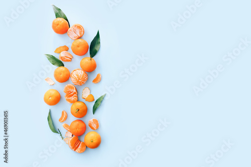 Fresh clementines with leaves on blue background, top view