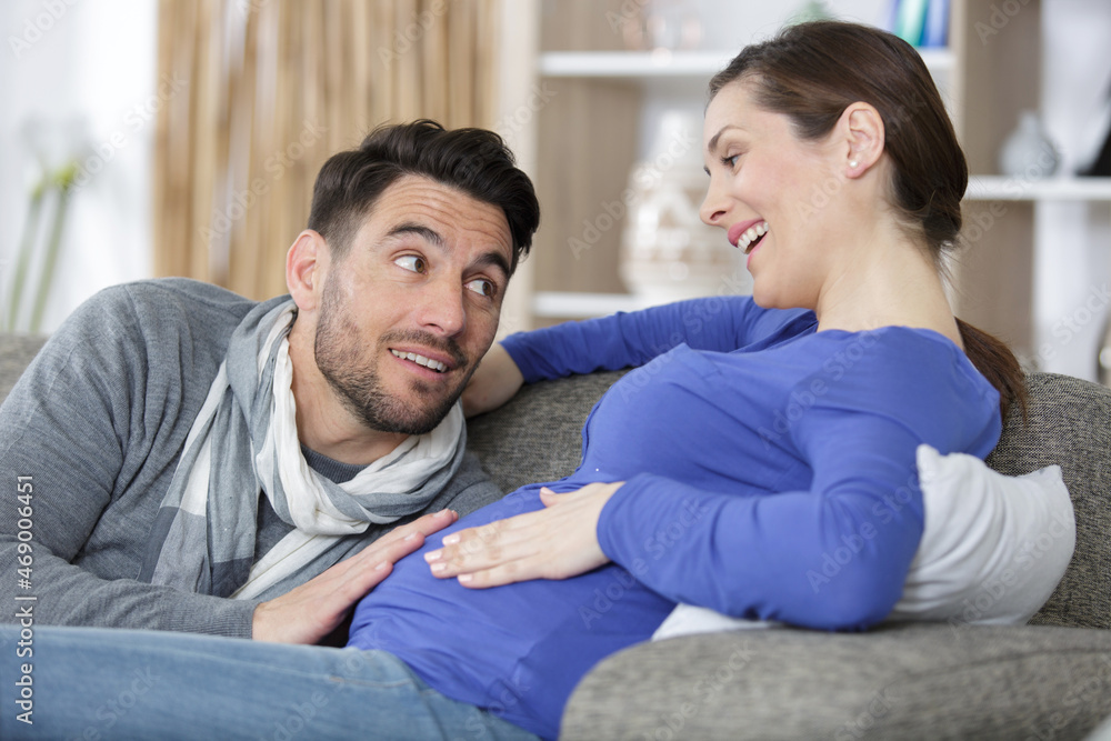 husband hugging and touching his wifes pregnant belly on sofa husband hugging and touching his wifes pregnant belly on sofa