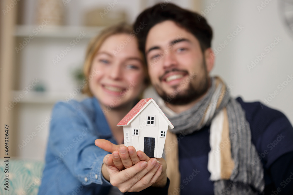 young happy couple holding small model house young happy couple holding small model house