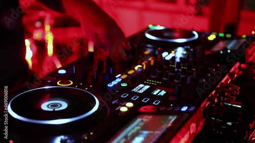Party dj plays techno music on rave party in club. Disc jockey performing in nightclub. Disk jokey mixing musical tracks with audio mixer