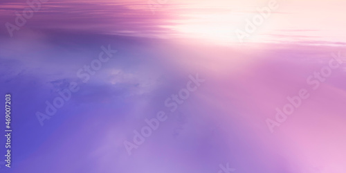 Seascape with the rising sun and pink and purple clouds reflected on the water.