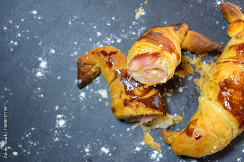 freshly baked croissants stuffed with ham and melted cheese, ready to eat, on a gray slate plate