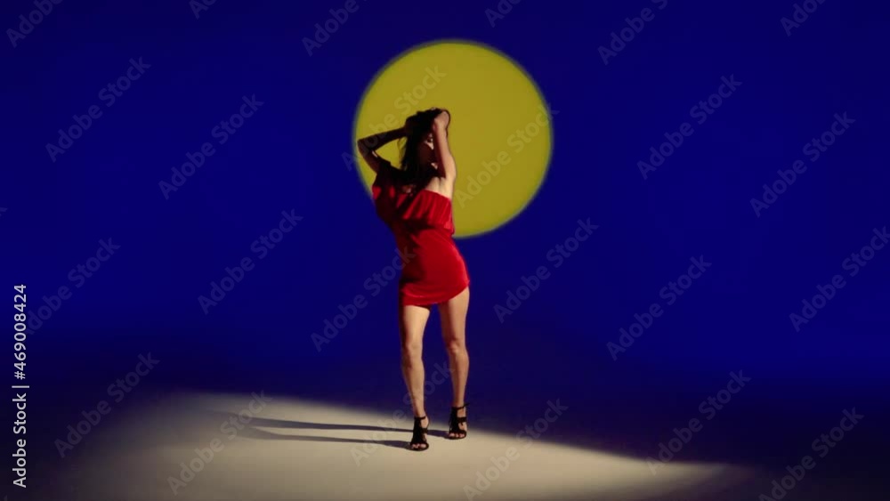 A beautiful Latino Woman dances in a red dress against a sunset background A beautiful Latino Woman dances in a red dress against a sunset background