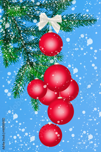 Christmas red balls with white ribbon on the background of fir branches, snowflakes and blue sky close up
