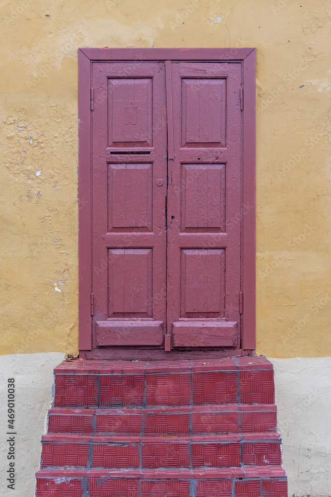 Fototapeta premium Red door on the background of a yellow wall