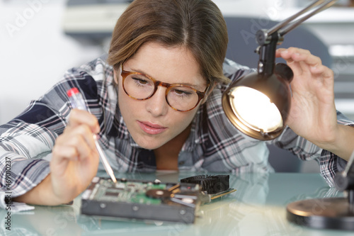 female computer technician directing lamp onto electronic component