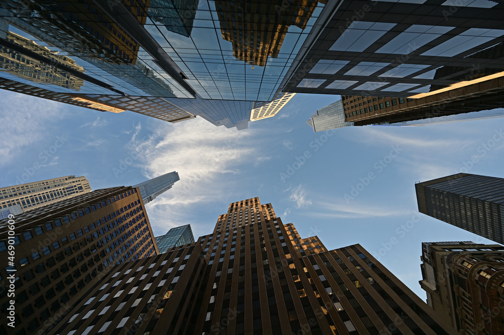 Upward view of skyscrapers in New York City, New York against early morning sky with high altitude clouds.