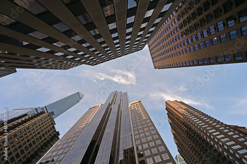 Upward view of skyscrapers in New York City, New York against early morning sky with high altitude clouds.