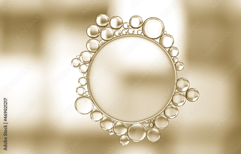 Obraz premium A unique pattern developed when oil droplets were added to a beaker of water to produce one large and numerous smaller bubbles surrounding the large one. Gold and white lighting enhanced the effect.