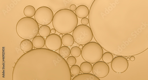 Oil droplets to surface of water to produce a different sized bubbles which have been highlighted by the effects ofpale yellow background