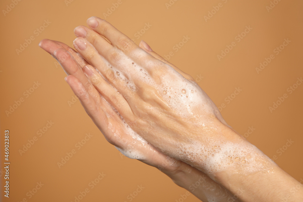 female hands with washing soap lather isolated on brown background
