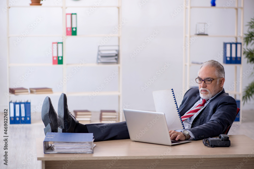 Old male employee working in the office Old male employee working in the office