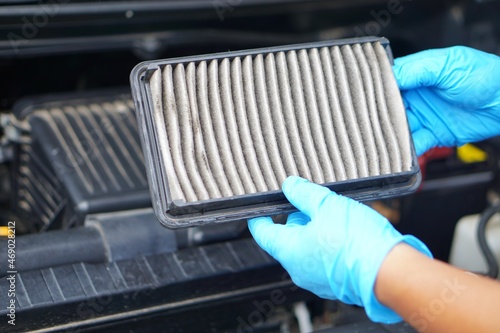 Mechanic's hands hold dusty and dirty air filter pad of car. Concept: checking and maintenance machine, car engine.
