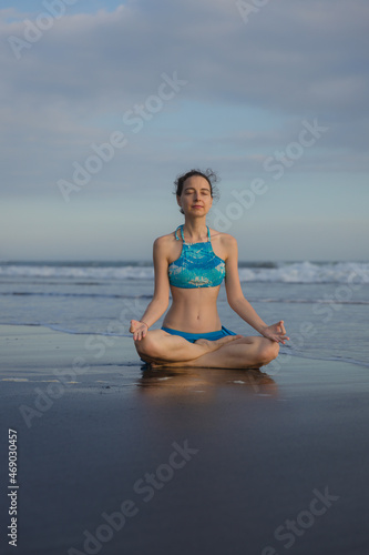 Yoga practice on the beach. Lotus pose. Padmasana. Hands in gyan mudra. Closed eyes. Meditation and concentration. Zen life. Relaxation of body and mind. Yoga retreat. Sunset time. Copy space.