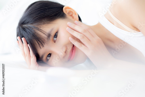 Beautiful of young asian woman smiling and lying on bed at bedroom  beauty of girl touch cheek with hygiene and healthy  cream and lotion  cosmetic and makeup  skin care and lifestyles concepts.