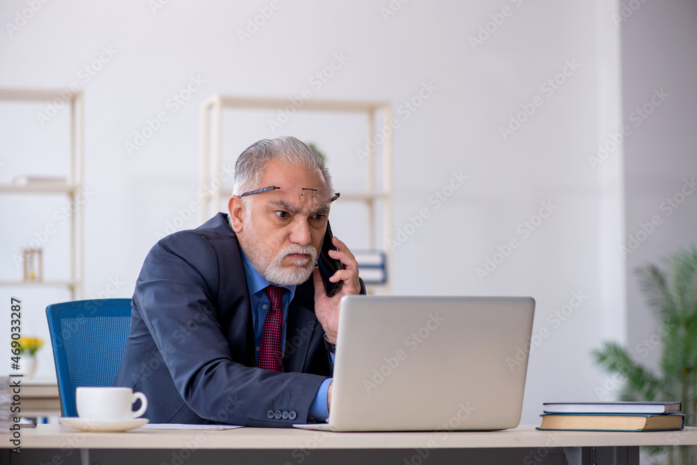 Old male employee working in the office Old male employee working in the office