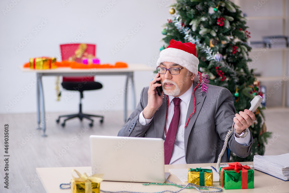 Aged male employee celebrating Christmas at workplace Aged male employee celebrating Christmas at workplace