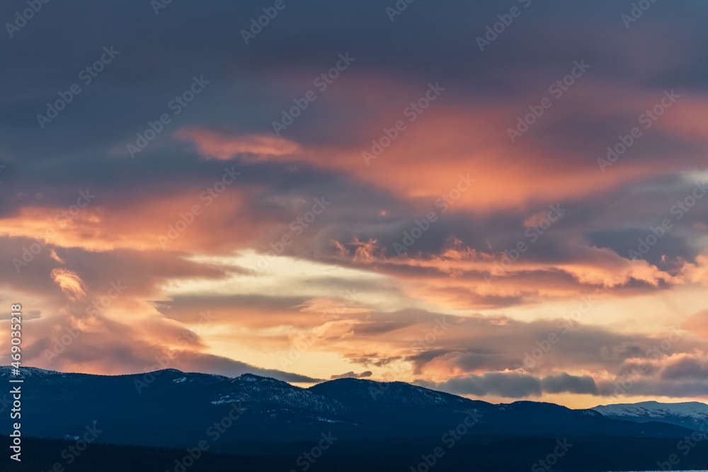 Pink aesthetic sunset vibes in fall, autumn with snow capped mountains in the distance and heavy, thick cloud cover. 