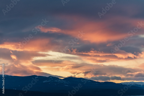 Pink aesthetic sunset vibes in fall, autumn with snow capped mountains in the distance and heavy, thick cloud cover. 