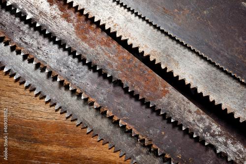 Old vintage metal saws for wood of different shapes and sizes, crumpled on a wooden background.