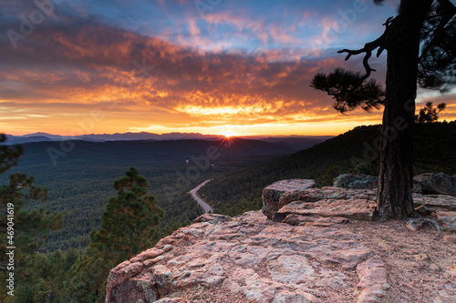 Arizona sunset, from the top of Mogollan Rim above Payson. Pine forest and highway below; Sunburst, brillian orange clouds and blue sky in distance. 
 photo