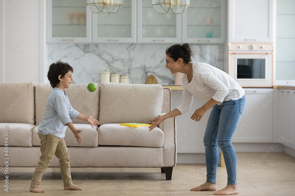Excited Indian mom playing active games with little son at home, throwing ball to kid in living room, enjoying leisure with preschool boy. Babysitter watching child, practicing activity on playtime Excited Indian mom playing active games with little son at home, throwing ball to kid in living room, enjoying leisure with preschool boy. Babysitter watching child, practicing activity on playtime